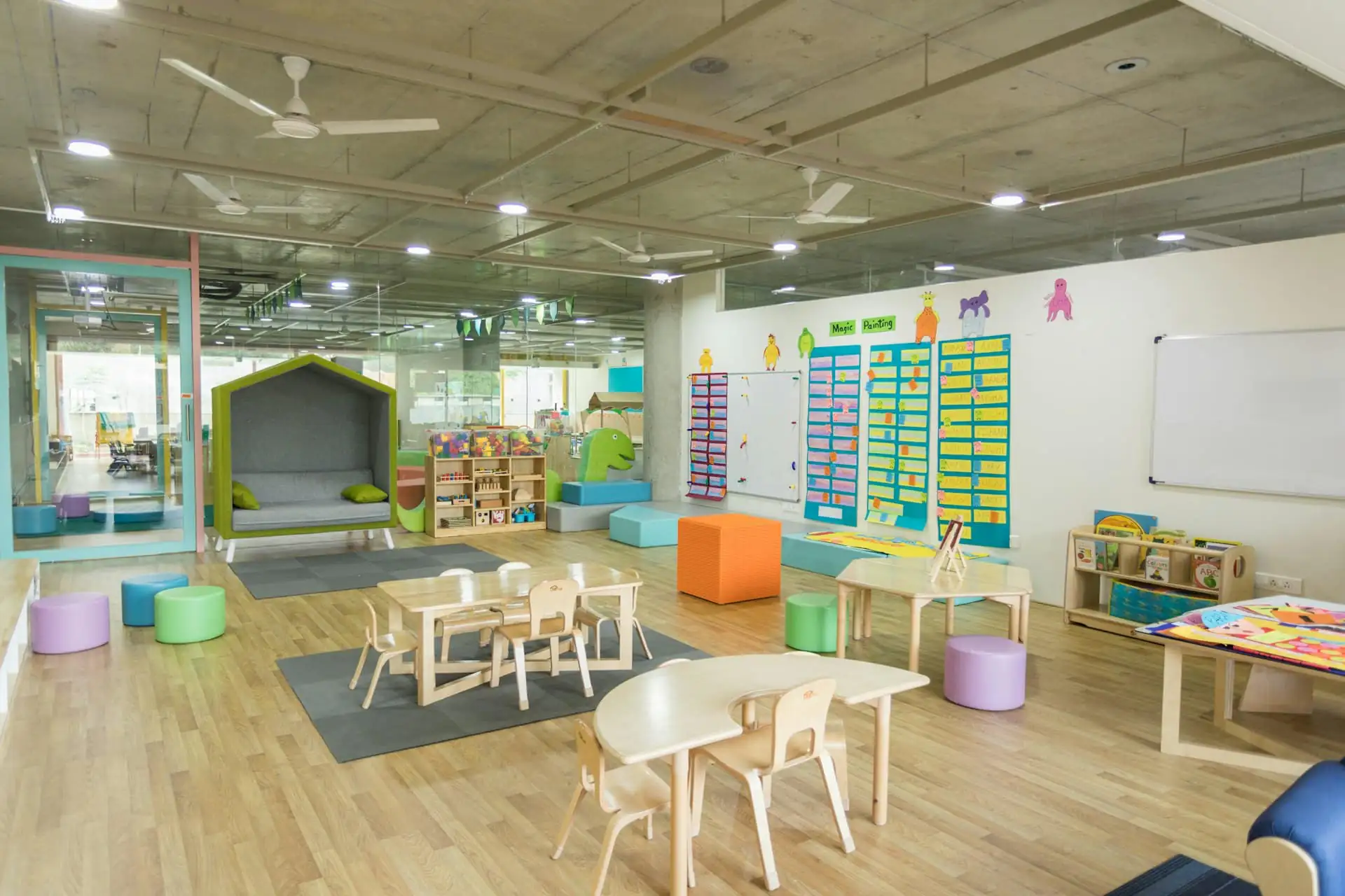 A bright, tidy nursery classroom with small tables and play corners